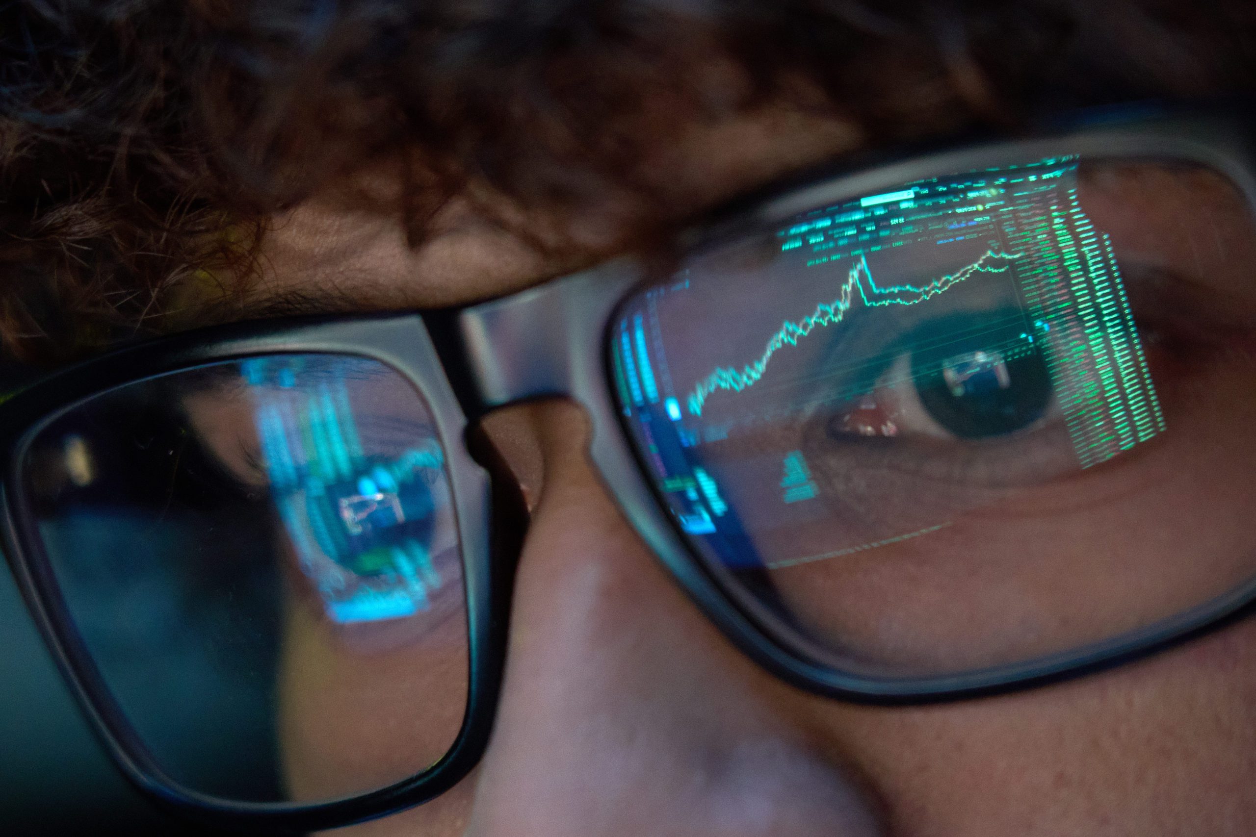 young-business-man-looking-at-trading-charts-reflecting-in-glasses-close-up
